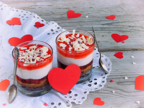Επιδόρπιο cheesecake σε γυάλινο βάζο σε ξύλινο φόντο: σοκολάτα, μπισκότο, αλατισμένα καραμέλα μαρμελάδα φράουλα, τυρί μους, σοκολάτα καθρέφτη λούστρο. Ημέρα του Αγίου Βαλεντίνου έννοια. Επιλεκτική εστίαση. Χώρο αντίγραφο — Φωτογραφία Αρχείου