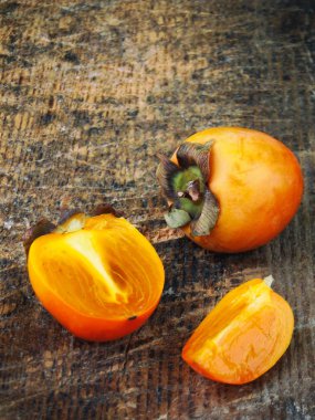 Ahşap arka plan üzerinde lezzetli olgun turuncu hurma. Seçici odak