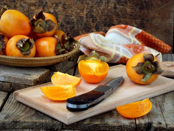Delicious ripe orange persimmons in bowl on wooden background. Selective focus — Stock Photo, Image