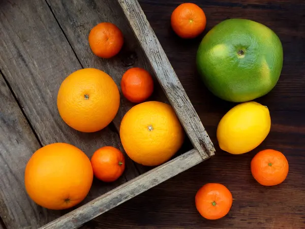 Különböző citrusfélék egy fadobozban: mandarin, citrom, narancs, kicsim. Nézd meg felülről — Stock Fotó