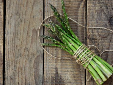 Ahşap arka planda bir sürü taze kuşkonmaz.