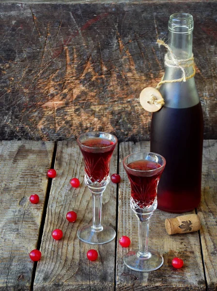 Tatlı kızılcık alkol içki likör iki bardak ve şişe üzerinde ahşap arka plan. Seçici odak — Stok fotoğraf