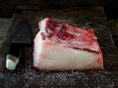 ham ahşap zemin üzerine tuz serpilir pastırma parçası.