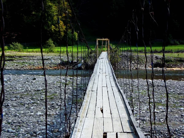 Hängende Holzbrücke über den Gebirgsfluss — Stockfoto
