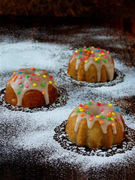 Muffins doces decorados com fondant e polvilhas multicoloridas. Cupcakes em um fundo escuro — Fotografia de Stock