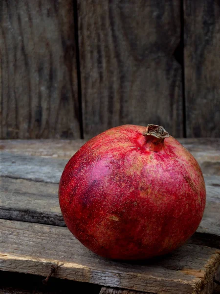 Reifer roter Granatapfel auf einem hölzernen Hintergrund — Stockfoto