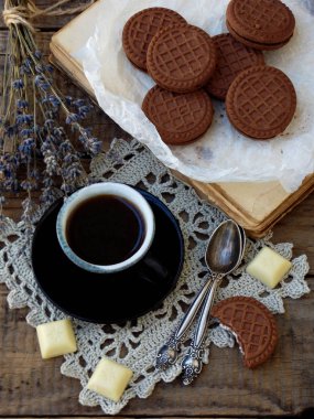 Çikolata kurabiye beyaz krema, fincan kahve ve buket ahşap arka plan üzerinde lavanta ile romantik bileşimi. Seçici odak.