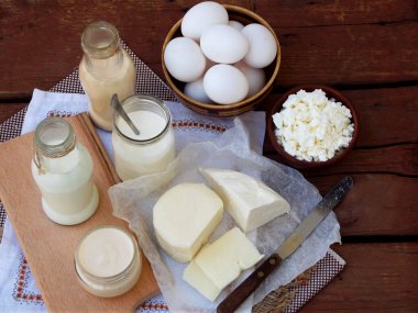 Ahşap arka plan üzerinde taze süt ürünleri kümesi: süt, peynir, yazlık, yoğurt, yumurta, mozzarella peyniri, ryazhenka, beyaz.