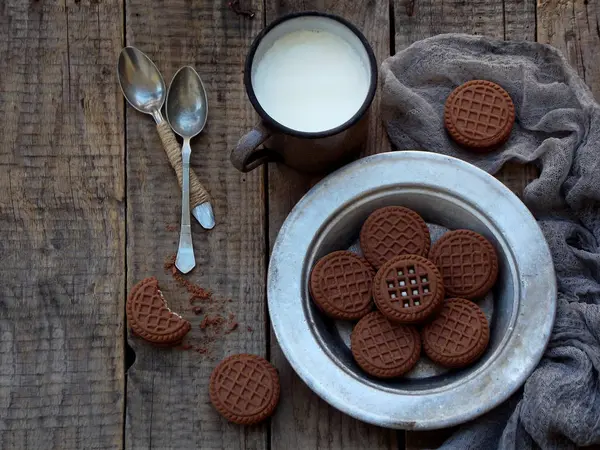 Schokoladenkekse mit weißer Sahne und einer Tasse Milch auf hölzernem Hintergrund. Selektiver Fokus. — Stockfoto