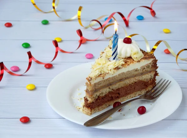Parça çikolatalı Muzlu Kek krem, çilek ve mum ışık ahşap arka plan üzerinde rozet ile dekore edilmiştir. Doğum günü. — Stok fotoğraf