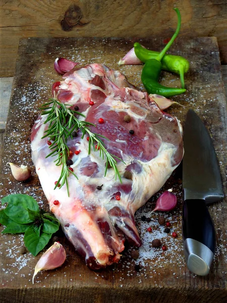 Carne fresca e cruda. Gamba di agnello con spezie su una tavola di legno con coltello per arrostire, stufare, barbecue , — Foto Stock