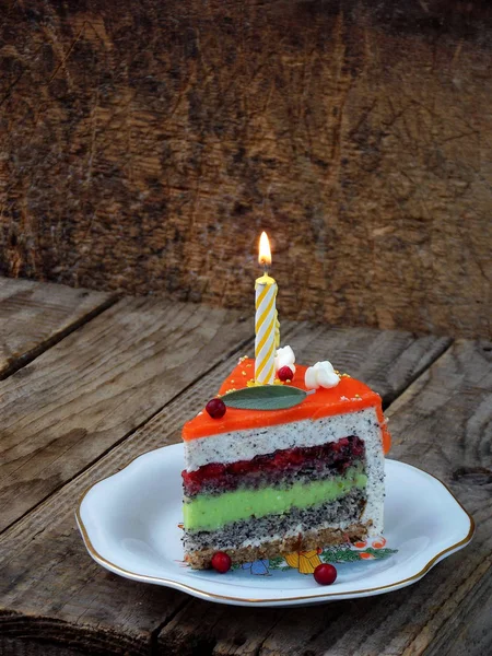 Morceau de gâteau au pavot avec crème au citron vert et gelée de fraises avec une bougie allumée. Joyeux anniversaire. focalisation sélective. espace de copie — Photo