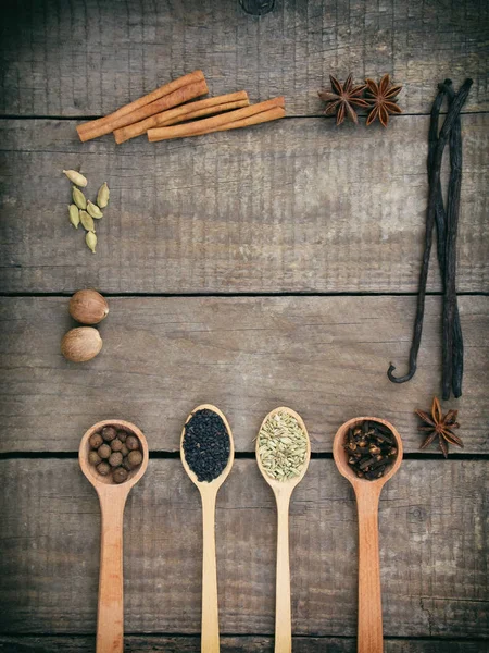 Composition of spices on wooden background: allspice, cloves, fennel, star anise, vanilla, cinnamon, green cardamom, nutmeg, black sesame. View from above. copy space — Stock Photo, Image