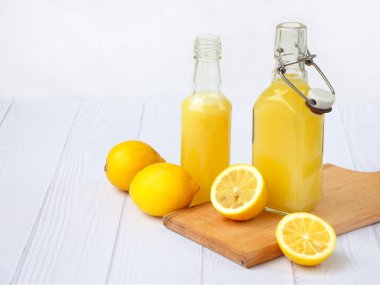 Taze sıkılmış limon suyu şişesi ve limon açık renkli. Vitamin içeceği veya kokteyl için. Seçici odak. Metin için yer