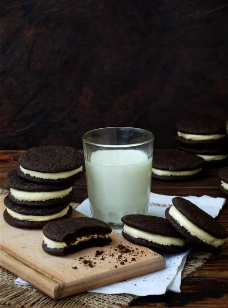 Hausgemachte Oreo-Schokoladenkekse mit weißer Marshmallow-Sahne und einem Glas Milch auf dunklem Hintergrund. Selektiver Fokus. — Stockfoto
