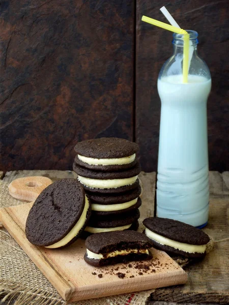 Hausgemachte Oreo-Schokoladenkekse mit weißer Marshmallow-Sahne und einer Flasche Milch auf dunklem Hintergrund. — Stockfoto