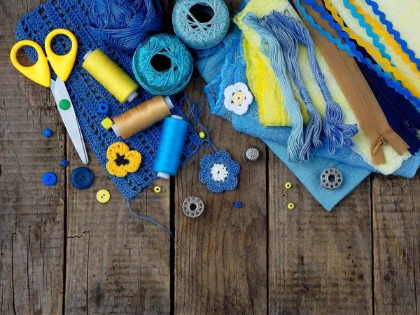 Gele en blauwe accessoires voor handwerk op bruin houten achtergrond. Breien, borduren, naaien. Kleine bedrijven. Inkomsten uit hobby. — Stockfoto