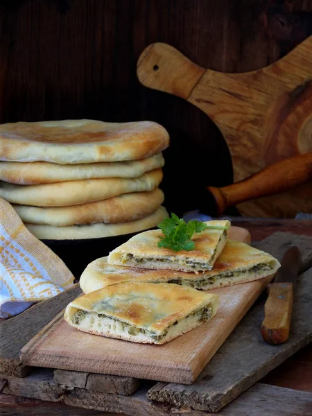 Ein Haufen georgischer Torten mit Käse und Frühlingsgemüse auf einem hölzernen Hintergrund. Raum für Text — Stockfoto