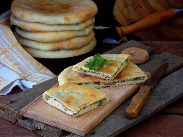 Ein Haufen georgischer Torten mit Käse und Frühlingsgemüse auf einem hölzernen Hintergrund — Stockfoto