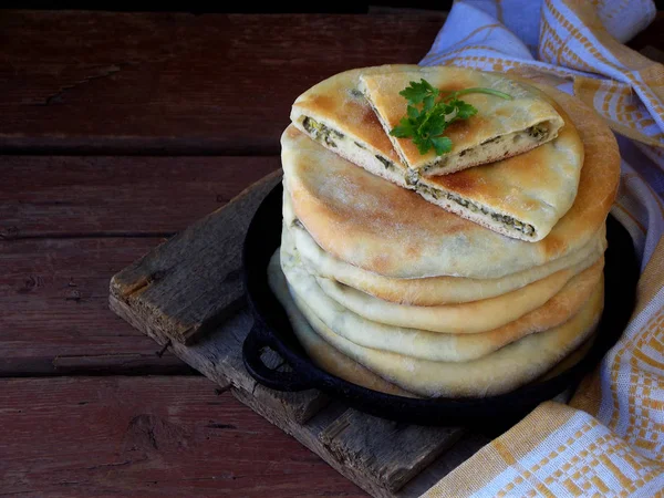 Ein Haufen georgischer Torten mit Käse und Frühlingsgemüse auf einem hölzernen Hintergrund. Raum für Text — Stockfoto