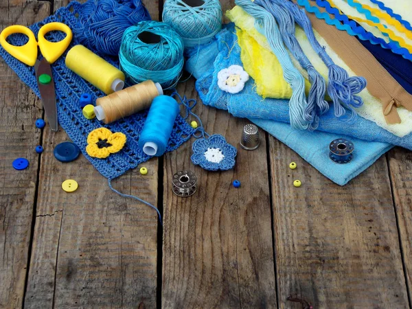 Gele en blauwe accessoires voor handwerk op bruin houten achtergrond. Breien, borduren, naaien. Kleine bedrijven. Inkomsten uit hobby. — Stockfoto