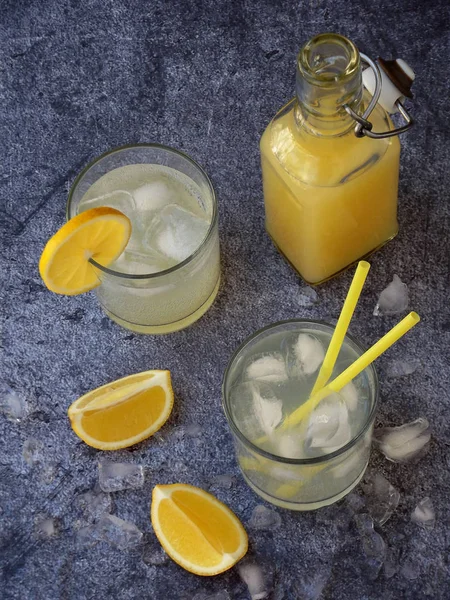 Twee glazen van koude zelfgemaakte limonade met citroen segmenten, ijsblokjes en rietjes op donkere achtergrond. Kopiëren van ruimte — Stockfoto