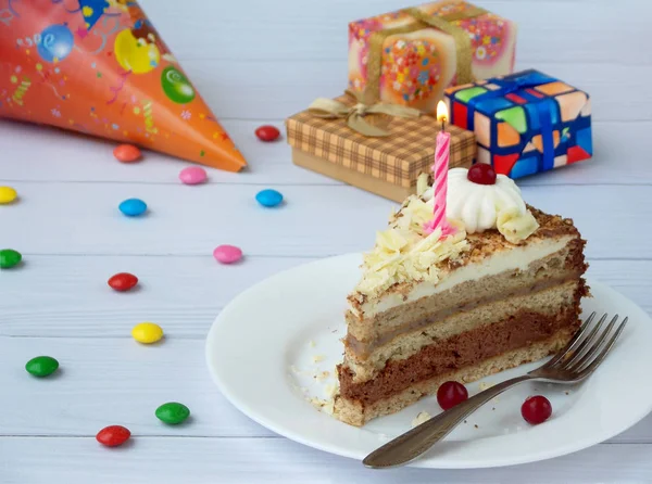 Parça çikolatalı Muzlu Kek krem, çilek ve mum ışık ahşap arka plan üzerinde rozet ile dekore edilmiştir. Doğum günü. — Stok fotoğraf