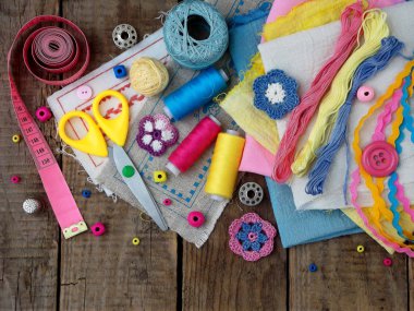 Pembe, sarı ve mavi aksesuarlar, iğne işi ahşap arka plan üzerinde. Örgü, nakış, dikiş. Küçük işletme. Hobi geliri.