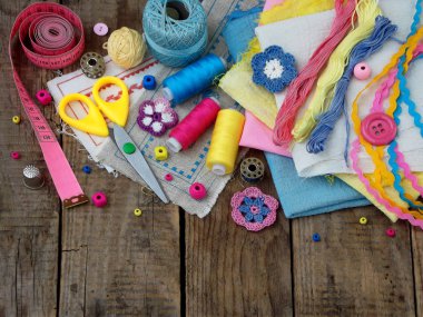 Pembe, sarı ve mavi aksesuarlar, iğne işi ahşap arka plan üzerinde. Örgü, nakış, dikiş. Küçük işletme. Hobi geliri.