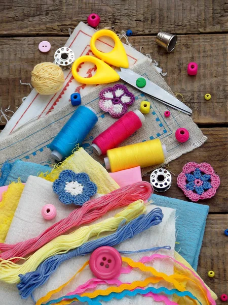 Accesorios rosa, amarillo y azul para la costura sobre fondo de madera. Tejer, bordar, coser. Pequeña empresa. Ingresos por hobby . — Foto de Stock