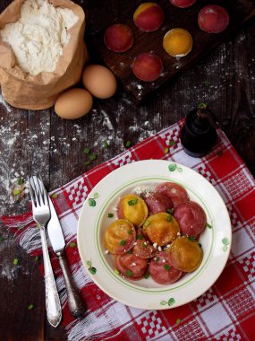 Taze pembe sarı pancar köfte veya koyu arka plan üzerinde ahşap tahta üzerinde tereyağı soslu ricotta peyniri ile doldurulmuş mantı.