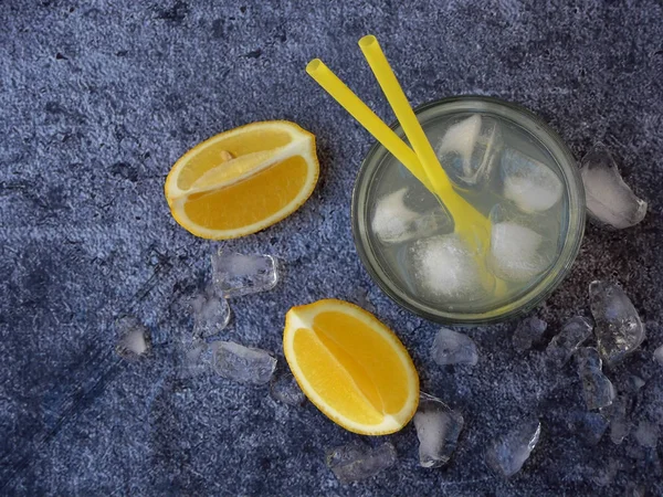 Een glas koude zelfgemaakte limonade met citroen segmenten, ijsblokjes en rietjes op donkere achtergrond. Kopiëren van ruimte — Stockfoto