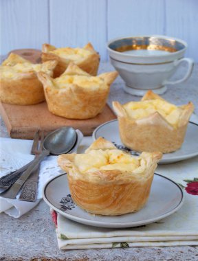 Tartlets hafif ahşap arka plan üzerinde süzme peynir ile. Mini kek puf böreği üzerinden. Peynirli kek.