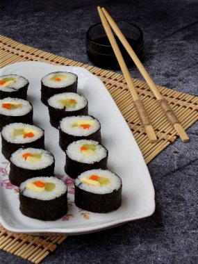 Suşi beyaz tabak, gri arka plan üzerinde. Geleneksel Asya gıda. Diyet sağlıklı gıda. Seçici odak. Metin için yer