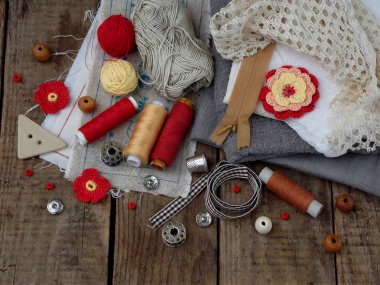 İğne işi ahşap arka plan üzerinde kırmızı ve gri aksesuarları. Örgü, nakış, dikiş. Küçük işletme. Hobi geliri.