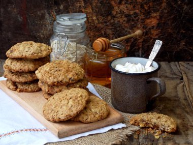 Unsuz gluten ücretsiz fıstık ezmesi, yulaf ezmesi, bal, kuru meyve çerezleri ve fincan kakao marshmallows ahşap arka plan ile. Yatay.