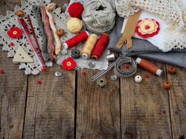 İğne işi ahşap arka plan üzerinde kırmızı ve gri aksesuarları. Örgü, nakış, dikiş. Küçük işletme. Hobi geliri.