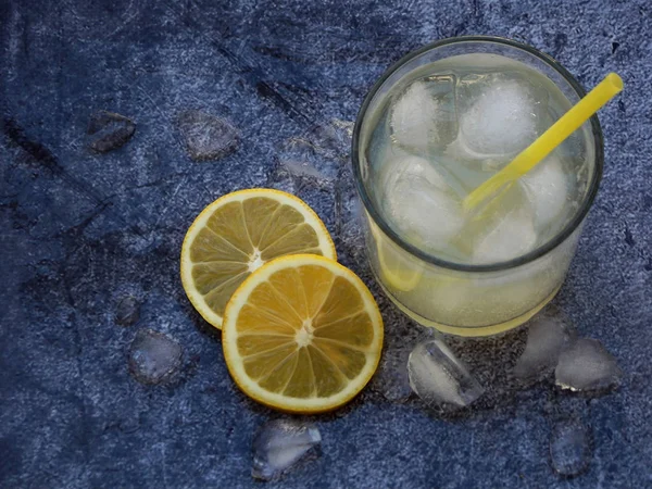 Glazen koude zelfgemaakte limonade met citroen segmenten, ijsblokjes en rietjes op donkere achtergrond. Kopiëren van ruimte — Stockfoto