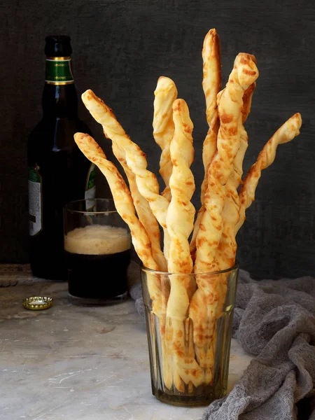 salty sticks of puff pastry sprinkled with cumin and Nigella on a wooden background