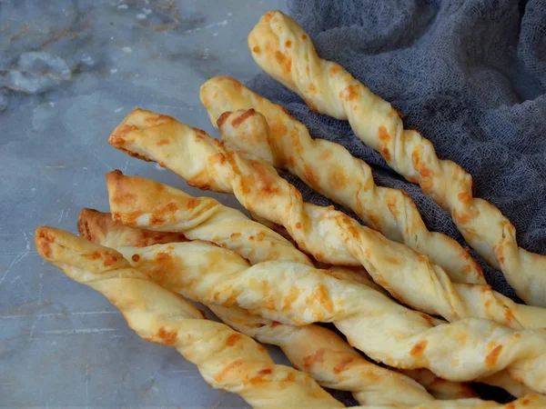 Salty sticks of puff pastry sprinkled with cumin and Nigella on a wooden background — Stock Photo, Image