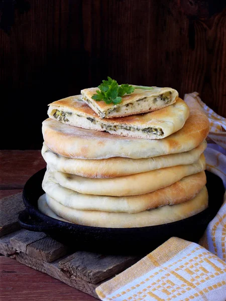 Pile of Georgian pies with cheese and spring greens on a wooden background — Stock Photo, Image