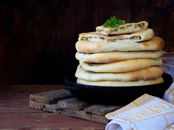 Stapel georgischer Torten mit Käse und Frühlingsgemüse auf einem hölzernen Hintergrund — Stockfoto