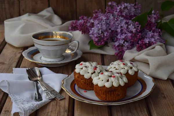 Composição romântica de buquê lilases brancos e roxos, cupcakes com creme de coalhada, xícaras de café em fundo de madeira . — Fotografia de Stock