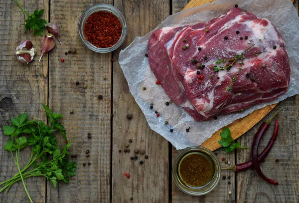 Carne cruda pezzo di carne di maiale e spezie marinata su sfondo di legno. Per bistecche, arrosti, stufati. Spazio per testo — Foto Stock