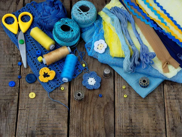 Κίτρινο και μπλε αξεσουάρ για κεντήματα σε ξύλινο υπόβαθρο. Πλέξιμο, κέντημα, ράψιμο. Μικρών επιχειρήσεων. Εισόδημα από χόμπι. — Φωτογραφία Αρχείου