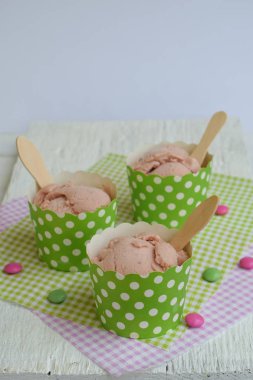 Pembe süt dondurma bir kağıt bardak beyaz ahşap zemin üzerinde. Berry sorbe. Metin için yer