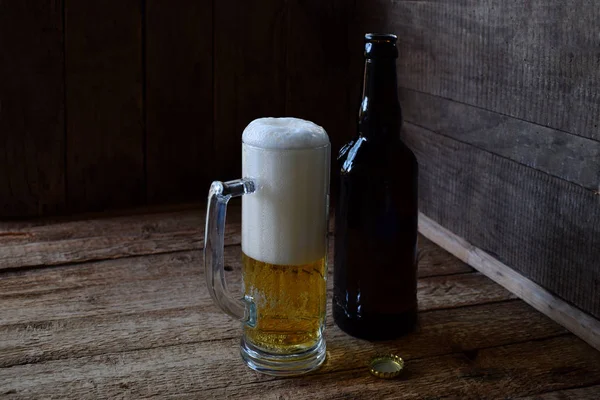 Taza de cerveza, botella sobre fondo de madera. Fotografiado con luz natural — Foto de Stock