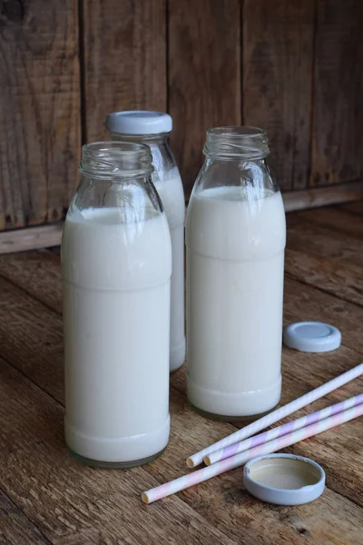 Boisson aigre-laitière ou yaourt en bouteille provenant des grains de kéfir et du lait sur fond de bois. Photographié à la lumière naturelle — Photo