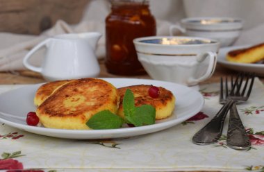 Ev yapımı yulaf süzme peynir kızartma krep. Reçel ve ahşap zemin üzerine ekşi krema ile Rus syrniki. Geleneksel kahvaltı