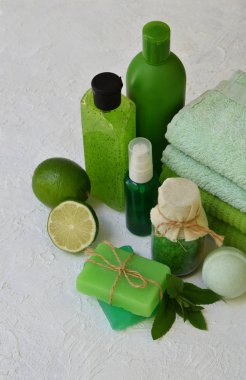 Kireç güzellik threatment ürünleri beyaz beton zemin üzerine yeşil renklerde nane bileşimi: şampuan, sabun, banyo tuzu, havlu, petrol. Çeşitli banyo aksesuarları. Spa için öğeleri.